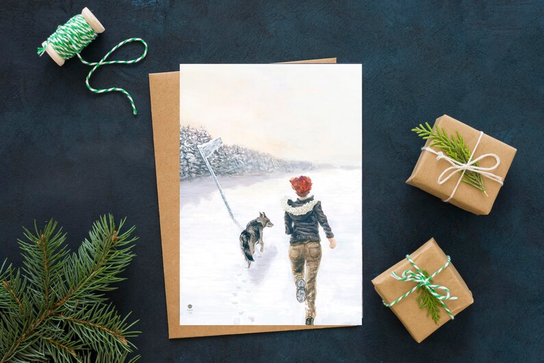 Op de afbeelding: Een aquarel van een vrouw en een hond die door een besneeuwd bos rennen. De vrouw draagt een rode hoed en een bruin jack. De hond is een grijs-witte wolfshond.