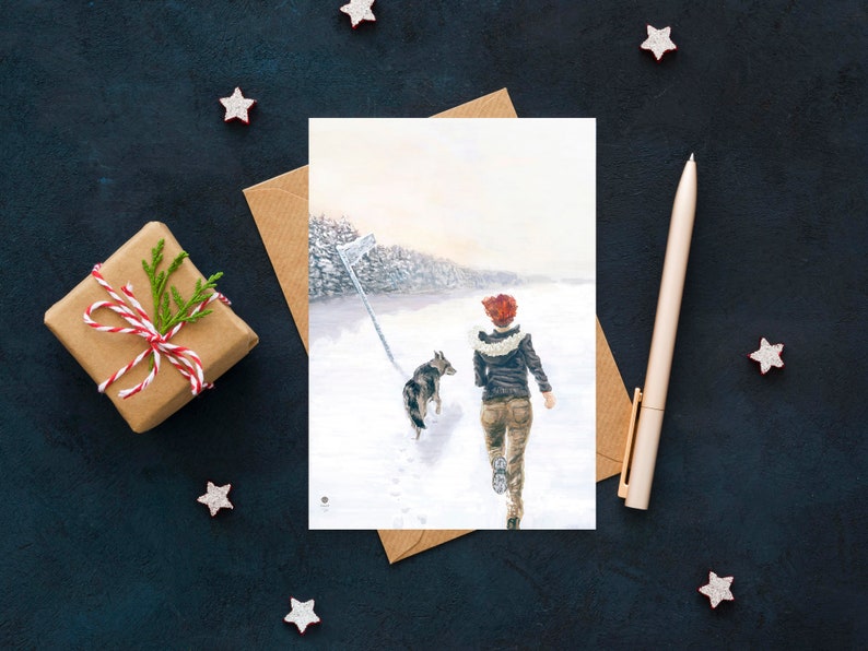 Op de afbeelding: Een aquarel schilderij van een vrouw die met een hond in een besneeuwd bos loopt. De vrouw draagt een rode hoed en een bruin jack. De hond is een grijs-witte husky.