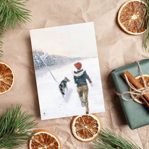 Op de afbeelding: Een kaart met een schilderij van een vrouw en een hond die door een besneeuwd bos lopen. De vrouw draagt een rode hoed en een bruin jack. De hond is een bruin-witte Duitse herder.
