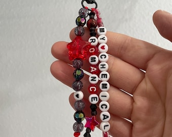 Könnte beinhalten: Ein Schlüsselanhänger mit Perlen mit den Worten "MY CHEMICAL ROMANCE" in weißen Buchstabenperlen. Der Schlüsselanhänger hat rote sternförmige Perlen, schillernde Perlen und einen schwarzen Verschluss.