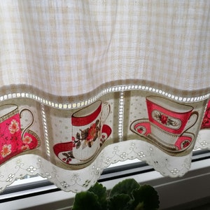 Könnte beinhalten: Eine weiße und beige Gingham-Gardine mit einem gewellten Saum und einer Spitzenborte. Die Gardine zeigt ein sich wiederholendes Muster von Teetassen mit Blumendesigns in den Farben Rosa, Rot und Grün.