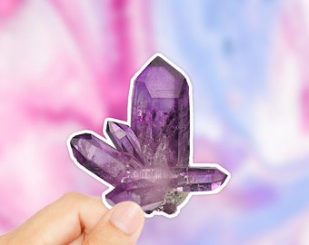 Könnte beinhalten: Ein Cluster aus violetten Amethyst-Kristallen mit einer spitzen Form. Die Kristalle sind in einem Cluster angeordnet, wobei die Spitzen der Kristalle nach oben zeigen. Die Kristalle sind von einer tiefvioletten Farbe und haben eine glänzende, glasartige Oberfläche.