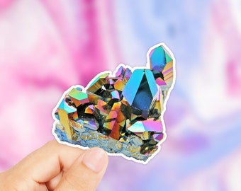 Könnte beinhalten: Ein farbenfroher Aufkleber mit einem Cluster aus schillernden Kristallen. Die Kristalle zeigen ein Spektrum an Farben, darunter Blau, Grün und Violett. Der Aufkleber wird von einer Hand gehalten.