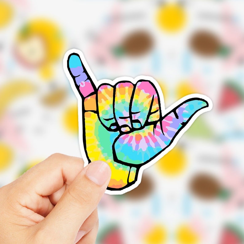 May include: A colorful tie-dye sticker of a hand making the shaka sign, a popular Hawaiian gesture of peace, aloha, and good vibes.