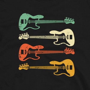 May include: Black t-shirt with a retro-style design of four bass guitars in green, yellow, orange, and red.