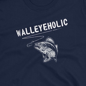 May include: Navy blue t-shirt with a white graphic of a walleye fish on a fishing line and the text "WALLEYEHOLIC".
