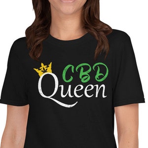 May include: A black t-shirt with a white graphic that says "CBD Queen" with a yellow crown above the text. The crown has green leaves.