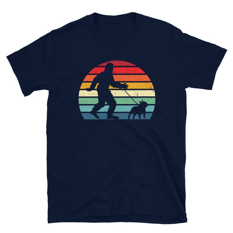 K&ouml;nnte beinhalten: Ein marineblaues T-Shirt mit einer Retro-Sonnenuntergangsgrafik, die eine Silhouette von Bigfoot zeigt, der einen Hund ausf&uuml;hrt.