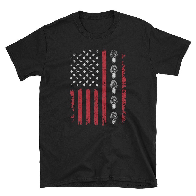 以下が含まれることがあります： 赤、白、青のアメリカ国旗のデザインが施された黒いTシャツ。旗は灰色のキノコの列で縁取られています。