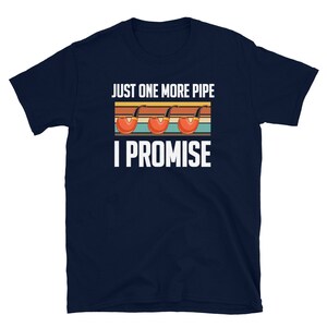 May include: Navy blue t-shirt with a vintage-style graphic of three pipes and the text "Just One More Pipe I Promise".