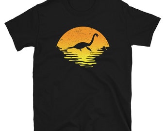 May include: Black t-shirt with a graphic of a silhouette of the Loch Ness Monster swimming in a sunset.