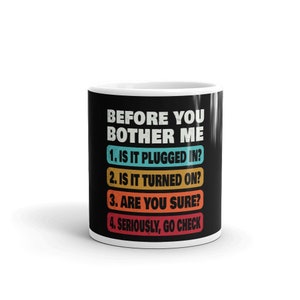 May include: Black coffee mug with white text that reads "Before you bother me 1. Is it plugged in? 2. Is it turned on? 3. Are you sure? 4. Seriously, go check"