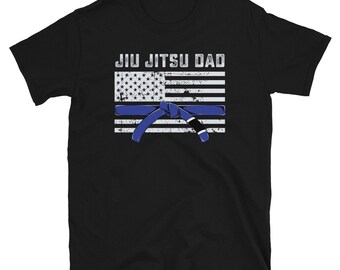 May include: Black t-shirt with the text "Jiu Jitsu Dad" and a graphic of an American flag with a blue jiu jitsu belt.