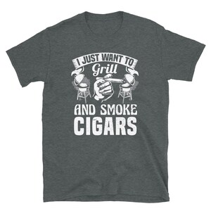 May include: A dark heather grey t-shirt with a white graphic that says "I just want to grill and smoke cigars". The graphic includes a hand holding a cigar and two grill silhouettes.
