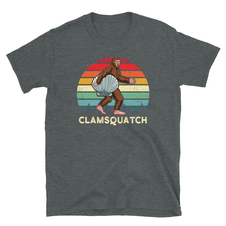 May include: A dark gray t-shirt with a retro sunset graphic featuring a Bigfoot carrying a large seashell. The text "CLAMSQUATCH" is printed below the graphic.