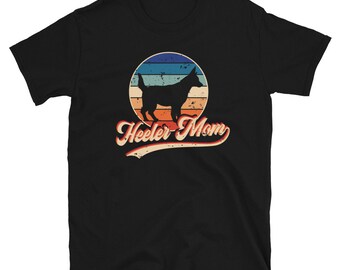May include: Black t-shirt with a retro-style graphic of a silhouette of a dog in a sunset-colored circle. The text "Heeler Mom" is below the circle.
