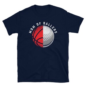 K&ouml;nnte beinhalten: Marineblaues T-Shirt mit einem wei&szlig;en und roten Basketball- und Golfball-Design. Der Text "MOM OF BALLERS" ist in Wei&szlig; auf das Shirt gedruckt.