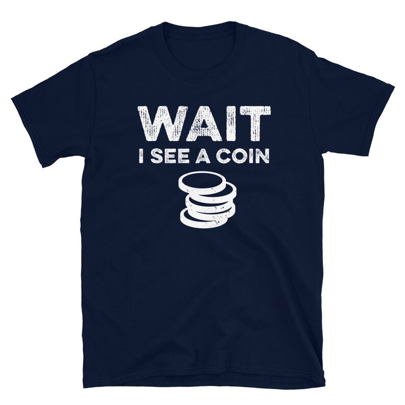 May include: A navy blue t-shirt with white text that reads "WAIT I SEE A COIN" and a stack of coins graphic.