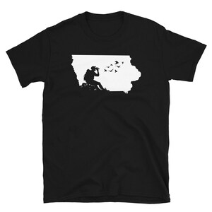 May include: Black t-shirt with a white silhouette of the state of Iowa and a person looking through binoculars with birds flying around them.