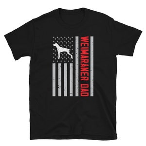 May include: Black t-shirt with a white Weimaraner dog silhouette and an American flag design. The text "Weimaraner Dad" is printed in red on the flag.