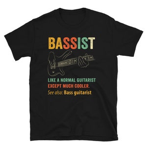 May include: Black t-shirt with a vintage-style graphic of a bass guitar and the text "Bassist Like a normal guitarist except much cooler. See also: Bass guitarist"