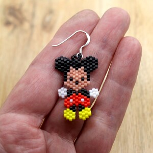 Peut inclure: Boucles d'oreilles Mickey Mouse en perles avec des oreilles noires, des gants blancs, un short rouge &agrave; pois blancs et des chaussures jaunes.