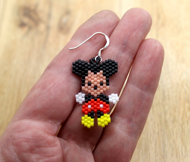 Peut inclure: Boucles d'oreilles Mickey Mouse en perles avec des oreilles noires, des gants blancs, un short rouge &agrave; pois blancs et des chaussures jaunes.