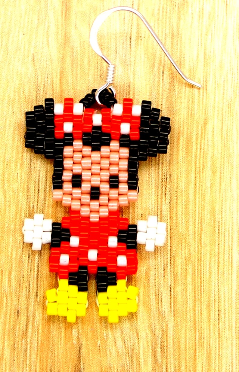 Peut inclure: Une paire de boucles d'oreilles en perles repr&eacute;sentant un dessin pixelis&eacute; de Minnie Mouse. Les boucles d'oreilles sont rouges, noires, blanches et jaunes. Les boucles d'oreilles sont attach&eacute;es &agrave; des crochets argent&eacute;s.