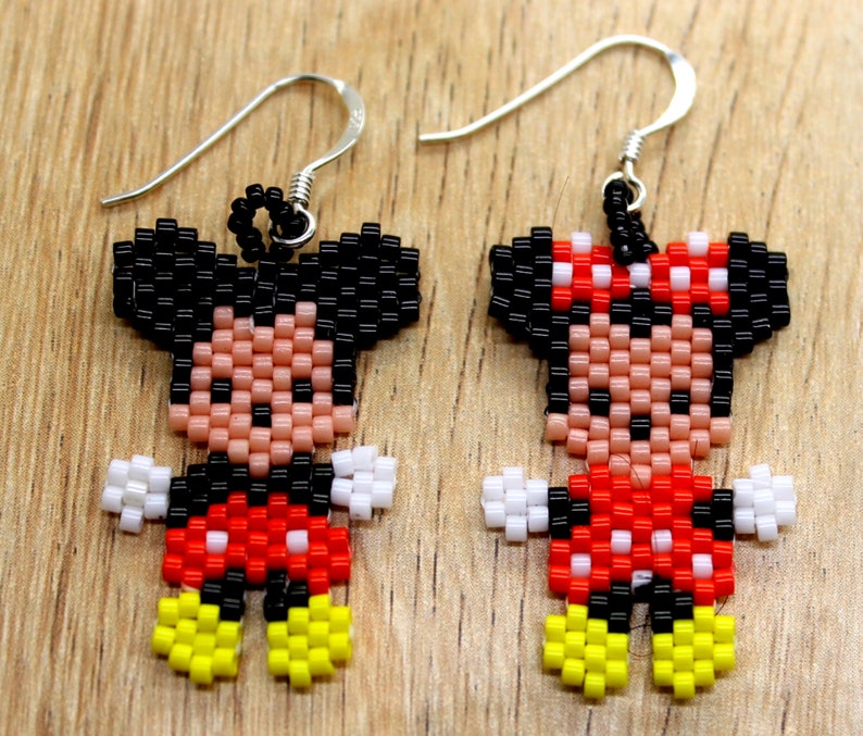 Peut inclure: Une paire de boucles d'oreilles en perles repr&eacute;sentant Mickey et Minnie Mouse. Les boucles d'oreilles sont faites de perles noires, blanches, rouges et jaunes. Les boucles d'oreilles sont suspendues &agrave; des crochets argent&eacute;s.