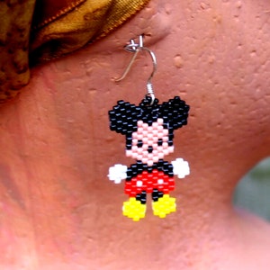 Peut inclure: Une paire de boucles d'oreilles en perles repr&eacute;sentant un personnage de dessin anim&eacute; avec des oreilles noires, un short rouge et des chaussures jaunes. Le personnage est Mickey Mouse.
