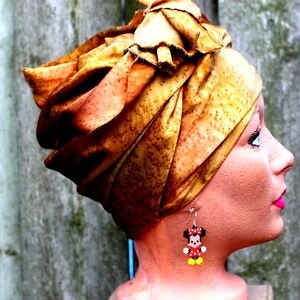 Peut inclure: Une t&ecirc;te de mannequin portant un turban couleur rouille avec une boucle d'oreille Minnie Mouse en perles. La boucle d'oreille est rouge, noire et jaune.