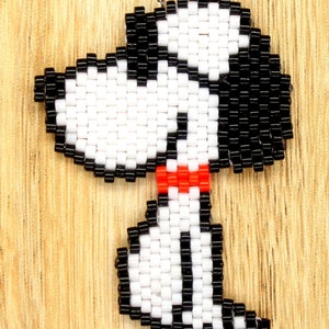 May include: Beaded earrings featuring a black and white cartoon dog with a red bow tie. The earrings are made with small, round beads and have a silver hook.