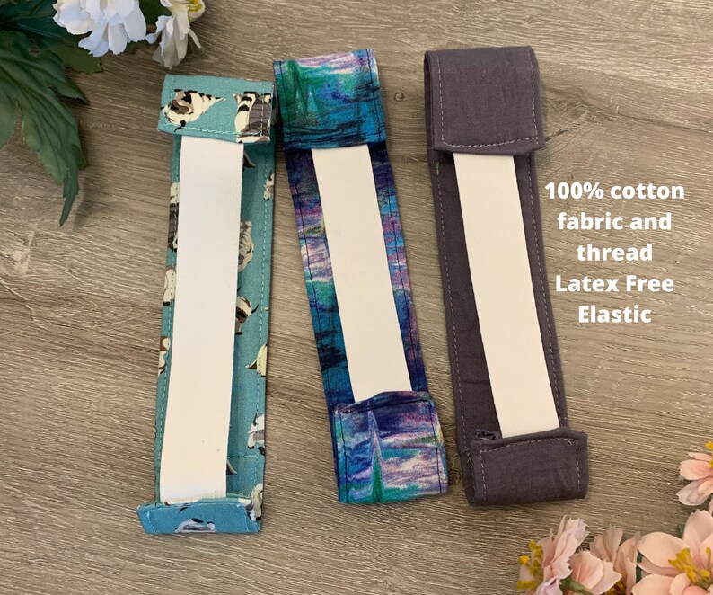 May include: Three headbands with different fabric patterns. The headband on the left has a blue and white pattern with small white dogs. The middle headband has a blue and purple watercolour pattern. The headband on the right is solid dark grey. All headbands have white elastic and are made with 100% cotton fabric and thread.  Latex Free Elastic.