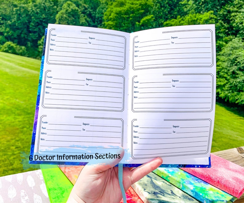 Peut inclure: Carnet ouvert avec six sections d'informations m&eacute;dicales. Chaque section comprend des champs pour le fournisseur, le nom, l'adresse, le t&eacute;l&eacute;phone, le fax, le diagnostic et les notes. Le carnet a une couverture sur le th&egrave;me de la galaxie bleue et violette et un ruban bleu clair.