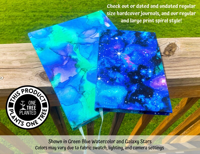 May include: Two hardcover journals with different covers. One journal has a blue and green watercolor design. The other journal has a galaxy print with blue, purple, and white stars. The journals are on a wooden surface. The text "This product plants one tree" is on a black circle sticker.