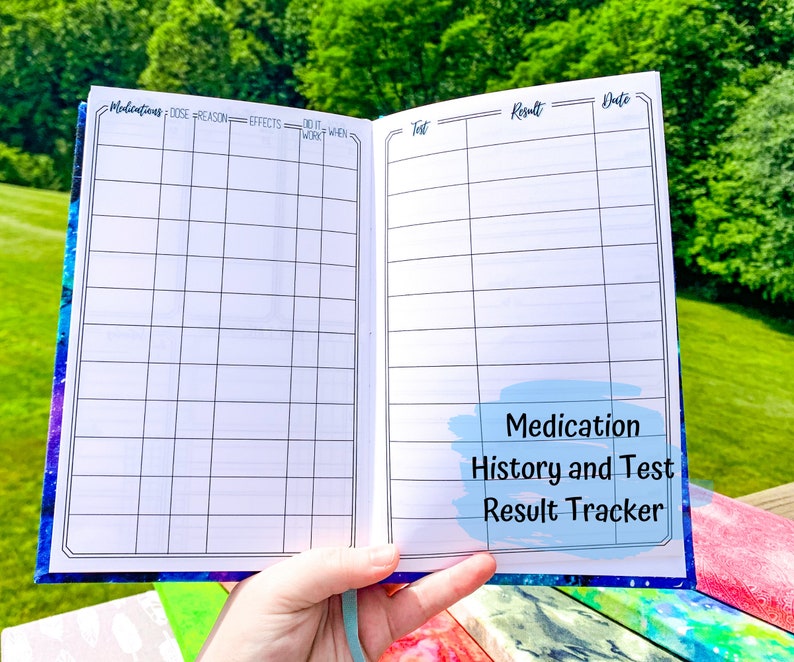 Peut inclure: Carnet ouvert avec un motif galaxie bleu et violet. Les pages int&eacute;rieures sont blanches avec des lignes de grille noires et des titres pour suivre les m&eacute;dicaments et les r&eacute;sultats des tests. Le texte "Medication History and Test Result Tracker" est visible.