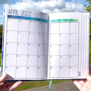 May include: A monthly planner with a white background and black grid lines. The month is April 2022. The days of the week are labeled at the top of the page. The planner has a section for notes on the right side.