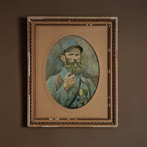 May include: A framed portrait of a man in a military uniform, with a beard and mustache, holding a pipe in his right hand. The portrait is set against a light brown background.