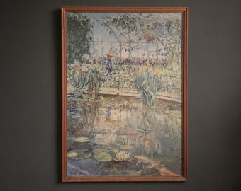 Pode incluir: Pintura emoldurada retratando uma serena cena de lagoa com nenúfares, peixes koi e uma figura ao fundo. A obra de arte está emoldurada em uma moldura de madeira e pendurada em uma parede cinza escura. As cores da pintura são suaves e suaves.