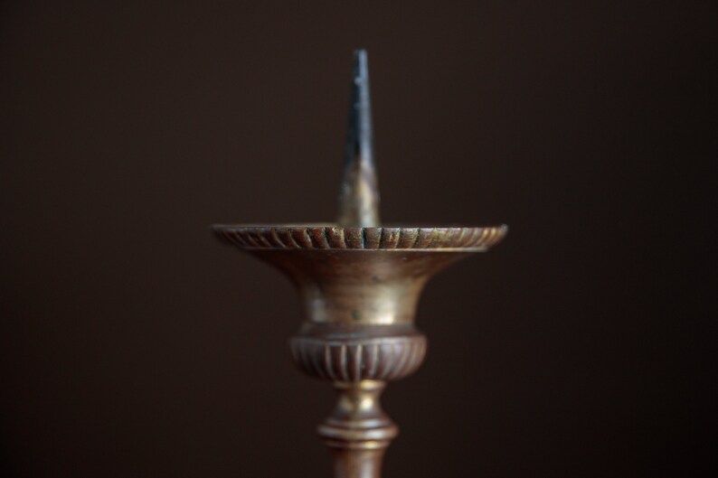 Puede incluir: Un candelero de lat&oacute;n vintage con una base acanalada decorativa y un solo portavelas.