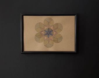 May include: A framed artwork featuring a symmetrical floral design. The artwork is composed of overlapping petal shapes in shades of green and brown, with a blue center. The frame is black, and the background is a dark wall.