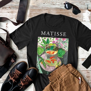 May include: Black t-shirt with a colorful painting of goldfish in a bowl by Henri Matisse. The painting is titled "Goldfish, 1912".