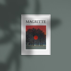 Può includere: Stampa artistica incorniciata con un paesaggio surrealista di Magritte. L'opera raffigura un sole rosso che tramonta dietro alberi silhouette contro un cielo rosso. La stampa è intitolata "MAGRITTE" con "Le Banquet, 1958" sotto.