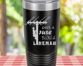 May include: Black stainless steel tumbler with a white silhouette of a lineman on a power pole and the text "Save a Fuse Blow a Lineman".