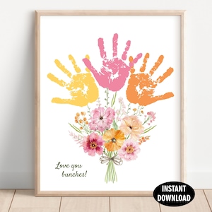 Può includere: Una stampa artistica verticale con tre impronte di mani in giallo, rosa e arancione disposte come petali sopra un bouquet ad acquerello di fiori rosa e arancioni con steli verdi. Il testo "Love you bunches!" è stampato in verde scuro.