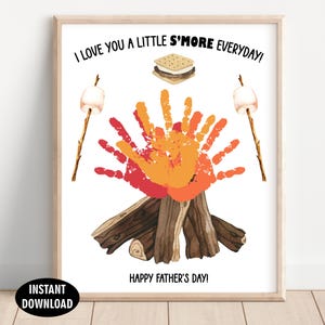 May include: A framed print with a watercolor illustration. The artwork features a campfire made of handprints in red and orange, with a s'more and marshmallows on sticks. Text reads "I LOVE YOU A LITTLE S'MORE EVERYDAY!" and "HAPPY FATHER'S DAY!"