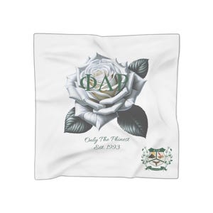 Puede incluir: Pañuelo cuadrado blanco con una gran rosa blanca y texto verde "ΦΔΡ". El pañuelo también incluye el texto "Only The Phinest Est. 1993" y un escudo verde y marrón. El pañuelo está hecho de una tela suave y fluida.