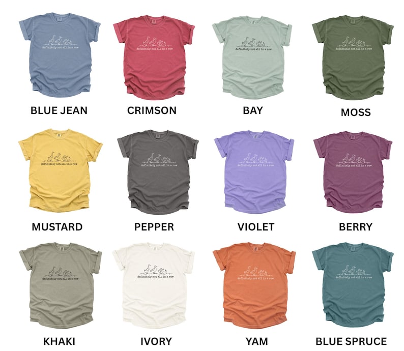 May include: A collection of twelve t-shirts in various colors, including blue jean, crimson, bay, moss, mustard, pepper, violet, berry, khaki, ivory, yam, and blue spruce. Each shirt features a white graphic and the text "Definitely not all a row."