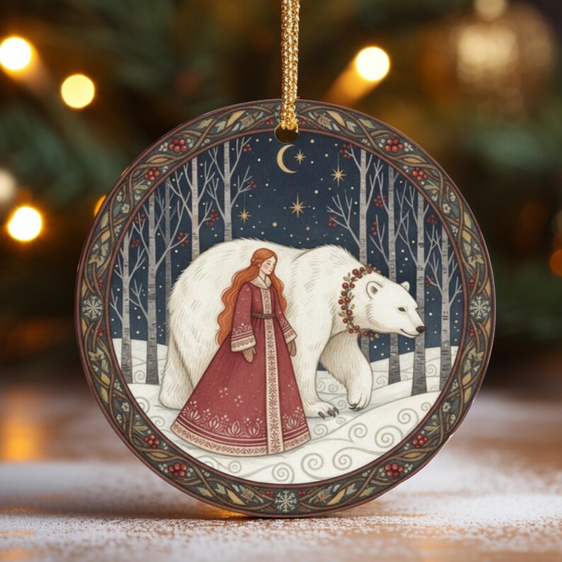 May include: A round ceramic ornament featuring a detailed illustration of a person with long red hair in a dark red dress walking beside a large white polar bear. The bear wears a berry wreath. The scene is set in a snowy forest under a crescent moon.