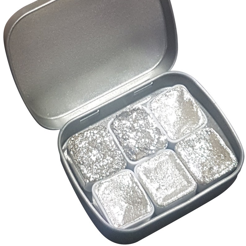 K&ouml;nnte beinhalten: Eine silberne Metalldose mit sechs silbernen Aquarellfarben-Pans. Die Dose ist ge&ouml;ffnet und die Farb-Pans sind sichtbar.